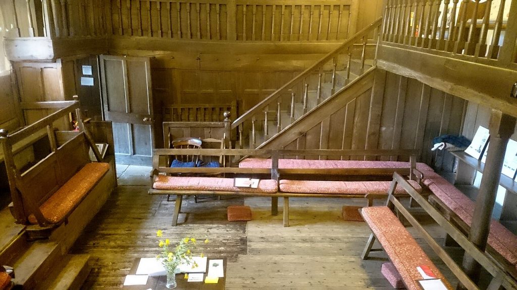 A historic meeting house interior showing wood benches used by families recorded in Quaker registers.