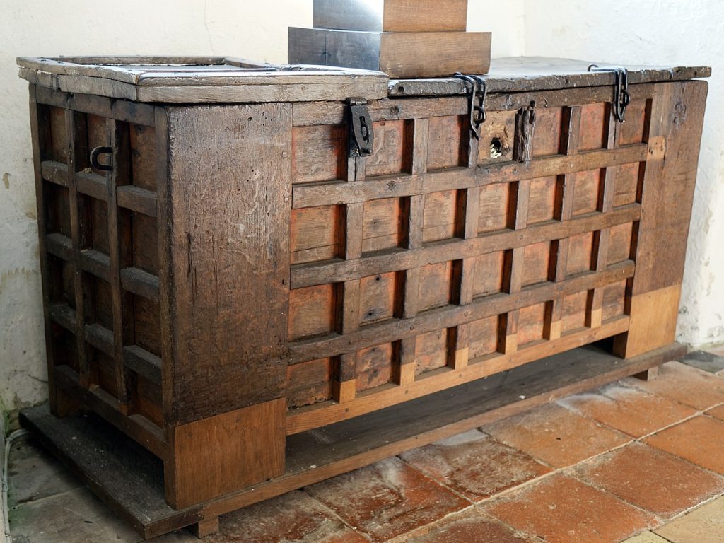 An old wooden parish chest with multiple locks inside a historic parish church holding parish chest records.